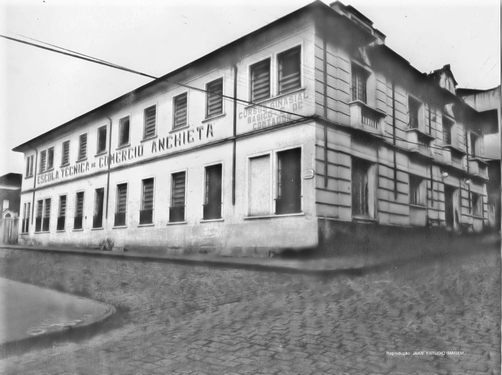 O prédio da Escola Técnica de Comércio Anchieta, com o nome pintado na fachada e o aviso do curso ginasial e de contador na esquina.